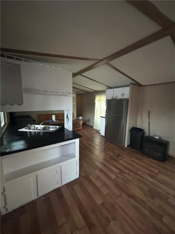 kitchen featuring white cabinetry, sink, dark hardwood / wood-style flooring, stainless steel fridge, and vaulted ceiling