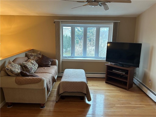 living room with light wood-type flooring, baseboard heating, and ceiling fan