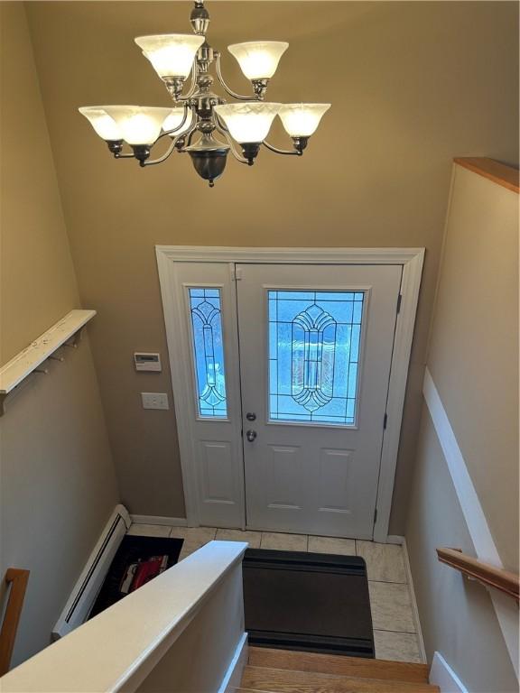 entryway featuring a notable chandelier, light tile patterned floors, and a baseboard heating unit