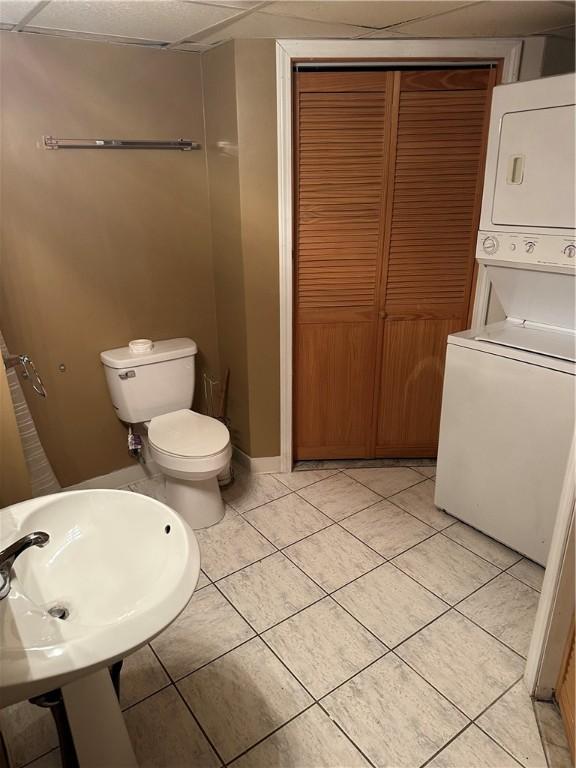 bathroom featuring sink, tile patterned flooring, stacked washer / drying machine, and toilet