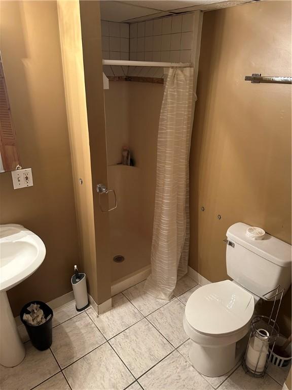 bathroom with tile patterned flooring, toilet, and curtained shower