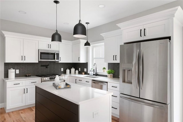 kitchen with white cabinetry, hanging light fixtures, a kitchen island, and stainless steel appliances