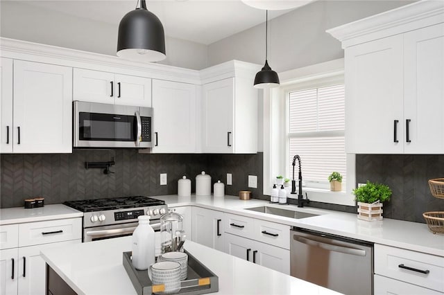 kitchen featuring appliances with stainless steel finishes, backsplash, sink, white cabinets, and hanging light fixtures