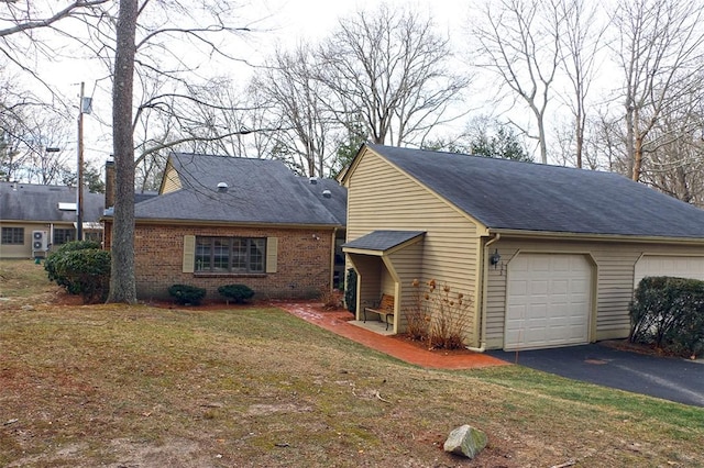 view of front of home with aphalt driveway, brick siding, roof with shingles, and a front yard