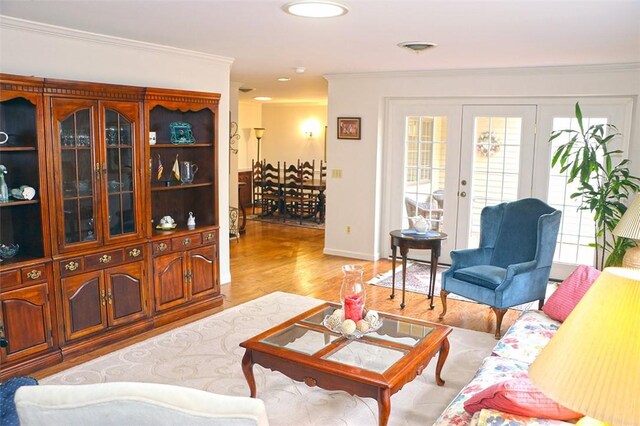 living room featuring visible vents, baseboards, crown molding, and light wood finished floors