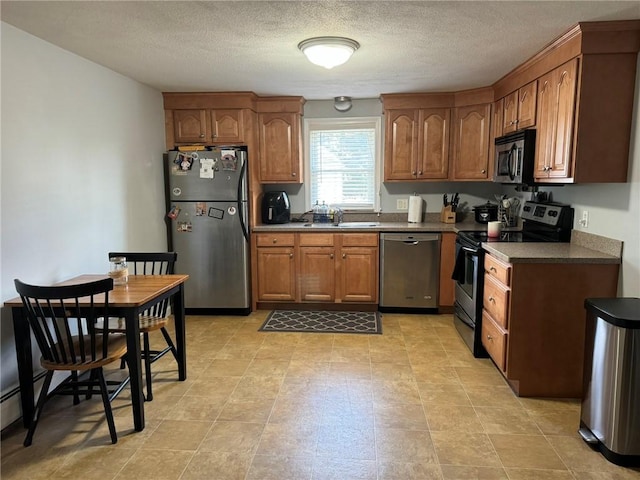 kitchen with a textured ceiling, sink, and stainless steel appliances