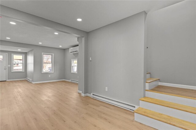 foyer with light hardwood / wood-style flooring, a wall unit AC, and a baseboard heating unit