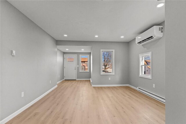 unfurnished room featuring a wall mounted air conditioner, light wood-type flooring, and a baseboard radiator