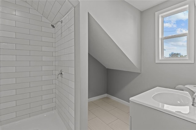 bathroom featuring a tile shower, tile patterned floors, and vanity