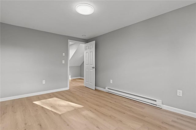 spare room with light wood-type flooring and a baseboard heating unit