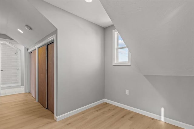 additional living space featuring light hardwood / wood-style floors and vaulted ceiling