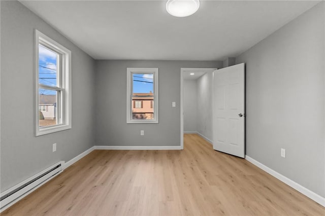 unfurnished bedroom featuring baseboard heating and light hardwood / wood-style flooring