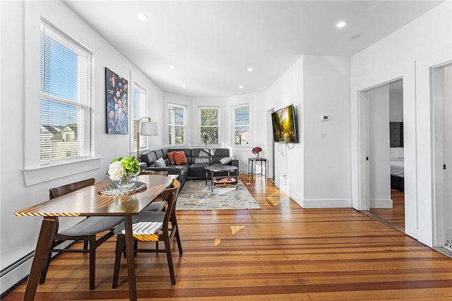 living room featuring wood-type flooring and a baseboard heating unit