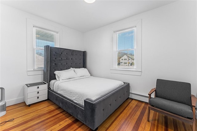 bedroom with wood-type flooring and a baseboard heating unit