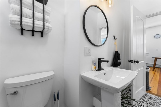 bathroom with toilet, baseboard heating, and sink