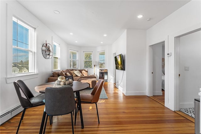 dining space featuring baseboard heating, light hardwood / wood-style flooring, and plenty of natural light