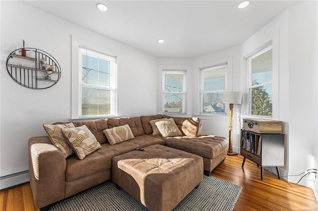 living room featuring baseboard heating, a healthy amount of sunlight, and wood-type flooring