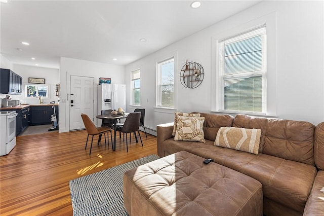 living room featuring wood-type flooring, a baseboard radiator, and sink