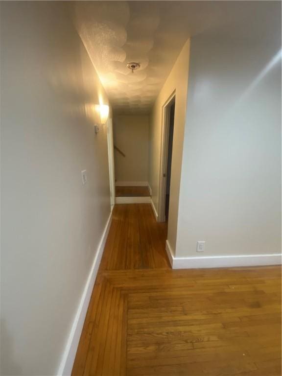 hall with baseboards and wood finished floors