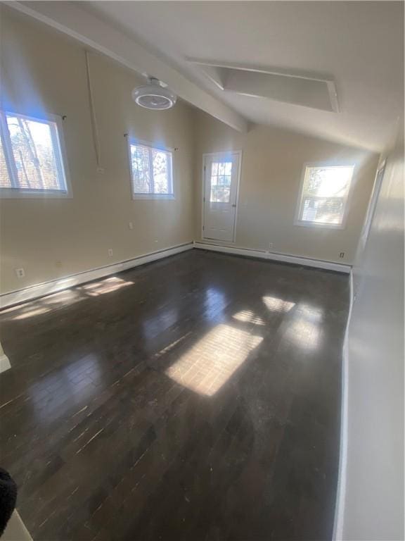 empty room with lofted ceiling with beams, wood finished floors, and baseboards