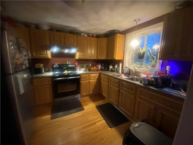 kitchen with a sink, hanging light fixtures, light wood-type flooring, freestanding refrigerator, and electric range oven