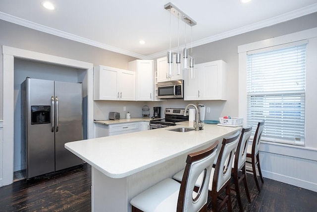 kitchen featuring kitchen peninsula, appliances with stainless steel finishes, dark hardwood / wood-style flooring, pendant lighting, and white cabinets