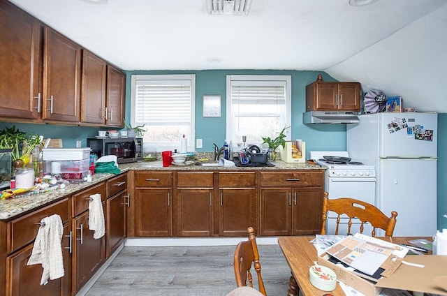 kitchen with white appliances, sink, vaulted ceiling, light stone countertops, and light wood-type flooring