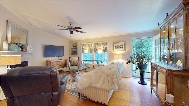 living room with ceiling fan, light wood-type flooring, crown molding, and lofted ceiling