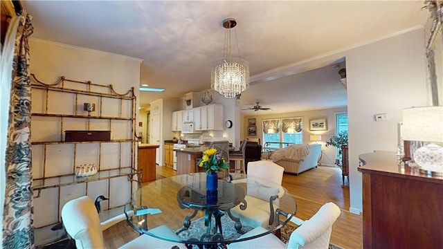 dining space featuring crown molding, light hardwood / wood-style flooring, and ceiling fan with notable chandelier