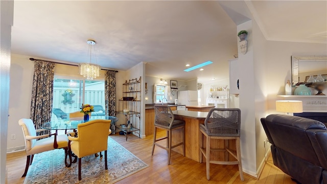 dining space with a notable chandelier, light wood-type flooring, and crown molding