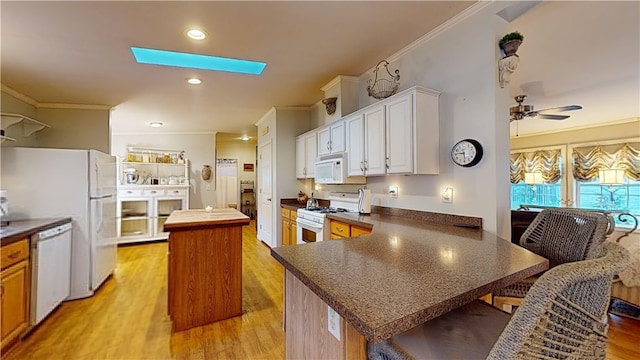 kitchen featuring kitchen peninsula, white appliances, ceiling fan, white cabinets, and a kitchen island