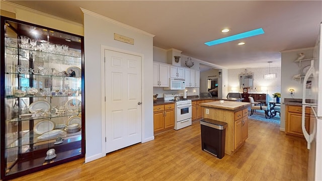 kitchen featuring white appliances, white cabinets, light wood-type flooring, decorative light fixtures, and a kitchen island