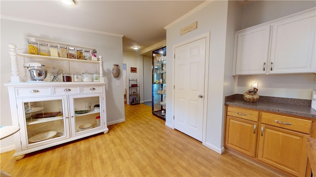 kitchen featuring white cabinets, light wood-type flooring, and ornamental molding