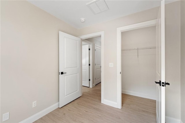 unfurnished bedroom with light wood-type flooring and a closet