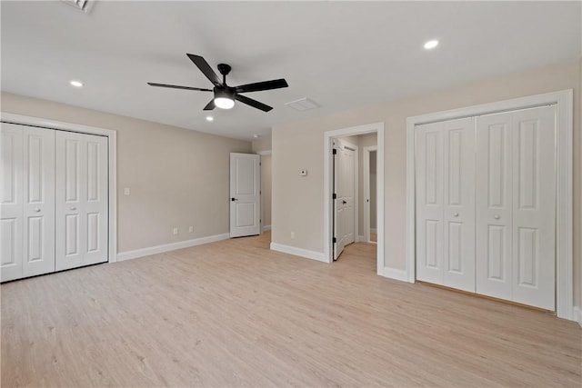 unfurnished bedroom with light wood-type flooring, ceiling fan, and multiple closets