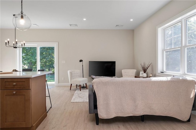 living room featuring a wealth of natural light, light hardwood / wood-style flooring, and a notable chandelier