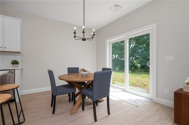 dining space with light hardwood / wood-style flooring and a chandelier