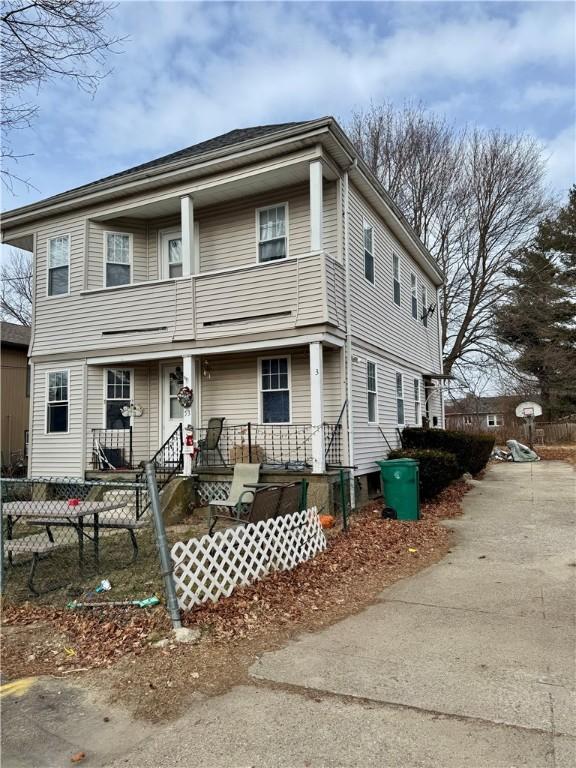 view of front facade with a porch, fence, and a balcony