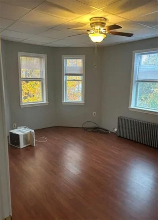 unfurnished room with radiator, ceiling fan, a drop ceiling, and dark hardwood / wood-style floors