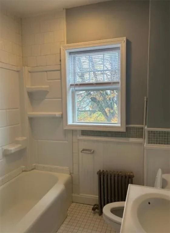 bathroom with tile patterned flooring, radiator heating unit, and toilet