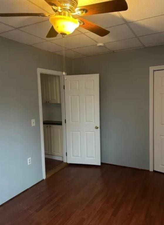 unfurnished room featuring a paneled ceiling, ceiling fan, and dark hardwood / wood-style floors