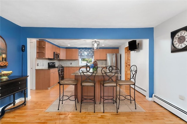 kitchen with decorative light fixtures, a center island, appliances with stainless steel finishes, and a baseboard radiator