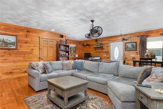 living room with light hardwood / wood-style floors and wood walls