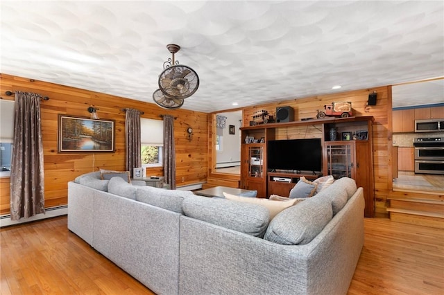 living room featuring wood walls, light hardwood / wood-style floors, and a baseboard heating unit