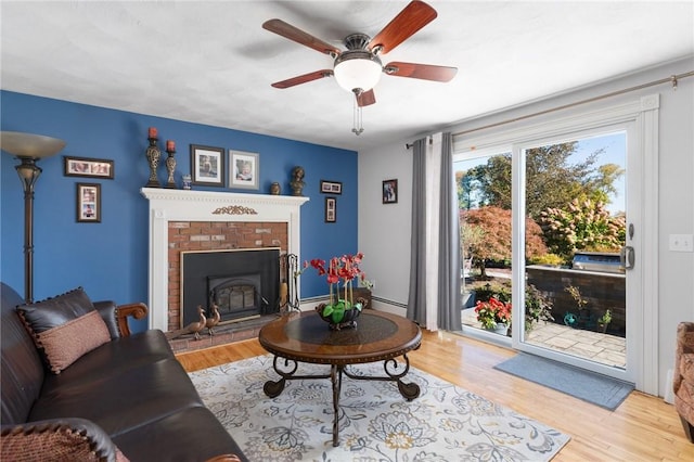 living room with ceiling fan, light wood-type flooring, a fireplace, and a baseboard radiator