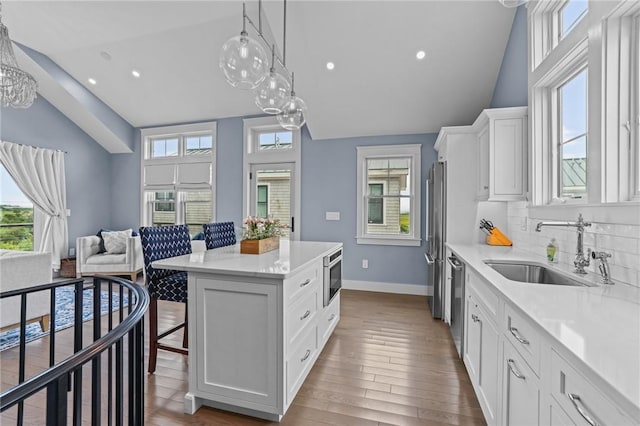 kitchen with white cabinets, a kitchen breakfast bar, sink, a kitchen island, and stainless steel appliances