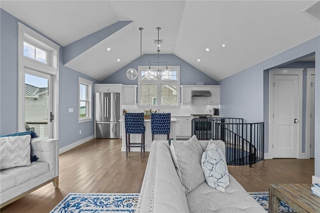 living room with vaulted ceiling, hardwood / wood-style floors, plenty of natural light, and a notable chandelier