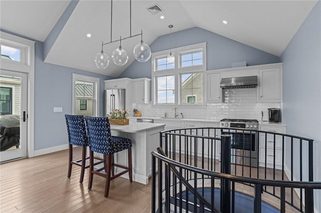 kitchen with white cabinetry, a center island, hanging light fixtures, stainless steel appliances, and exhaust hood