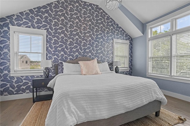 bedroom with multiple windows, hardwood / wood-style floors, and vaulted ceiling