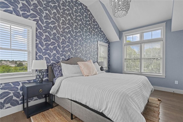 bedroom with a chandelier, hardwood / wood-style flooring, and lofted ceiling